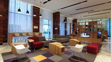 A modern lobby with seating areas, a television, and a bookshelf.