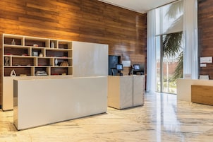 A modern reception area with a wooden wall, a marble floor, and a digital check-in station.