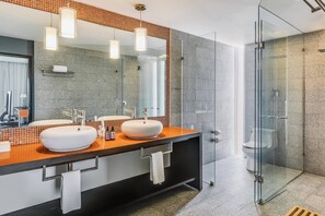 A modern bathroom with two sinks, a glass shower enclosure, and a large mirror.