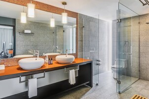 Un baño moderno con dos lavamanos, cabina de ducha de vidrio y un espejo grande.