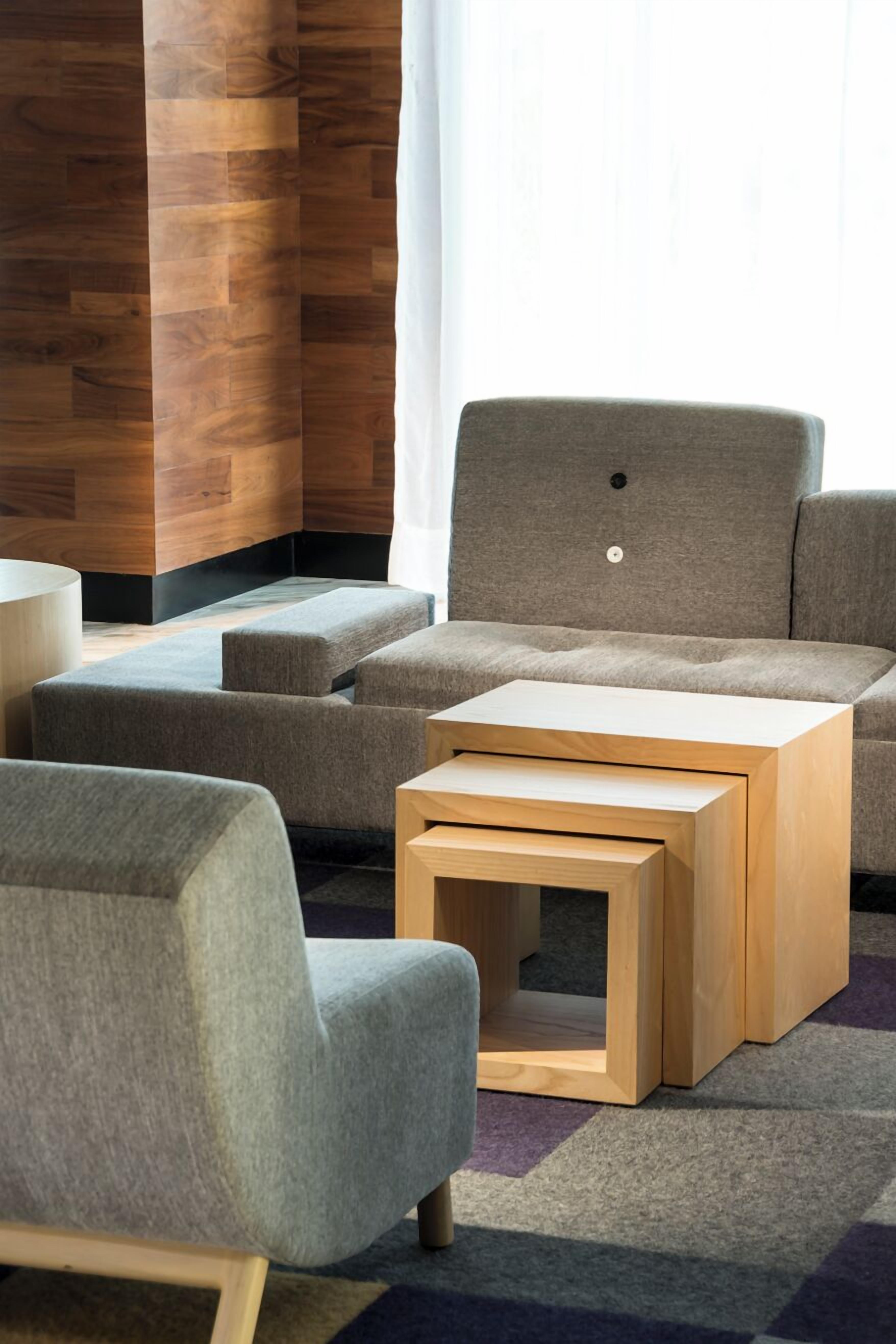 Una sala de estar moderna con un sofá gris, dos sillones grises y una mesa de centro de madera.