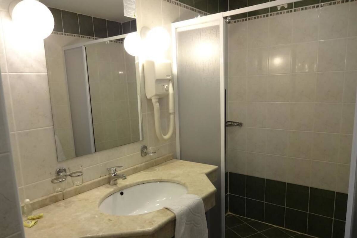 A bathroom with a sink, mirror, and shower.
