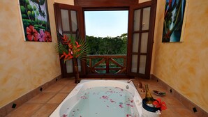 Ein Badezimmer mit einer großen Badewanne, einem hölzernen Balkon und einem Wandbild im tropischen Stil.