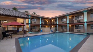 A hotel with a pool, outdoor seating, and a covered patio area. - Best Western Desert Winds (Mojave)