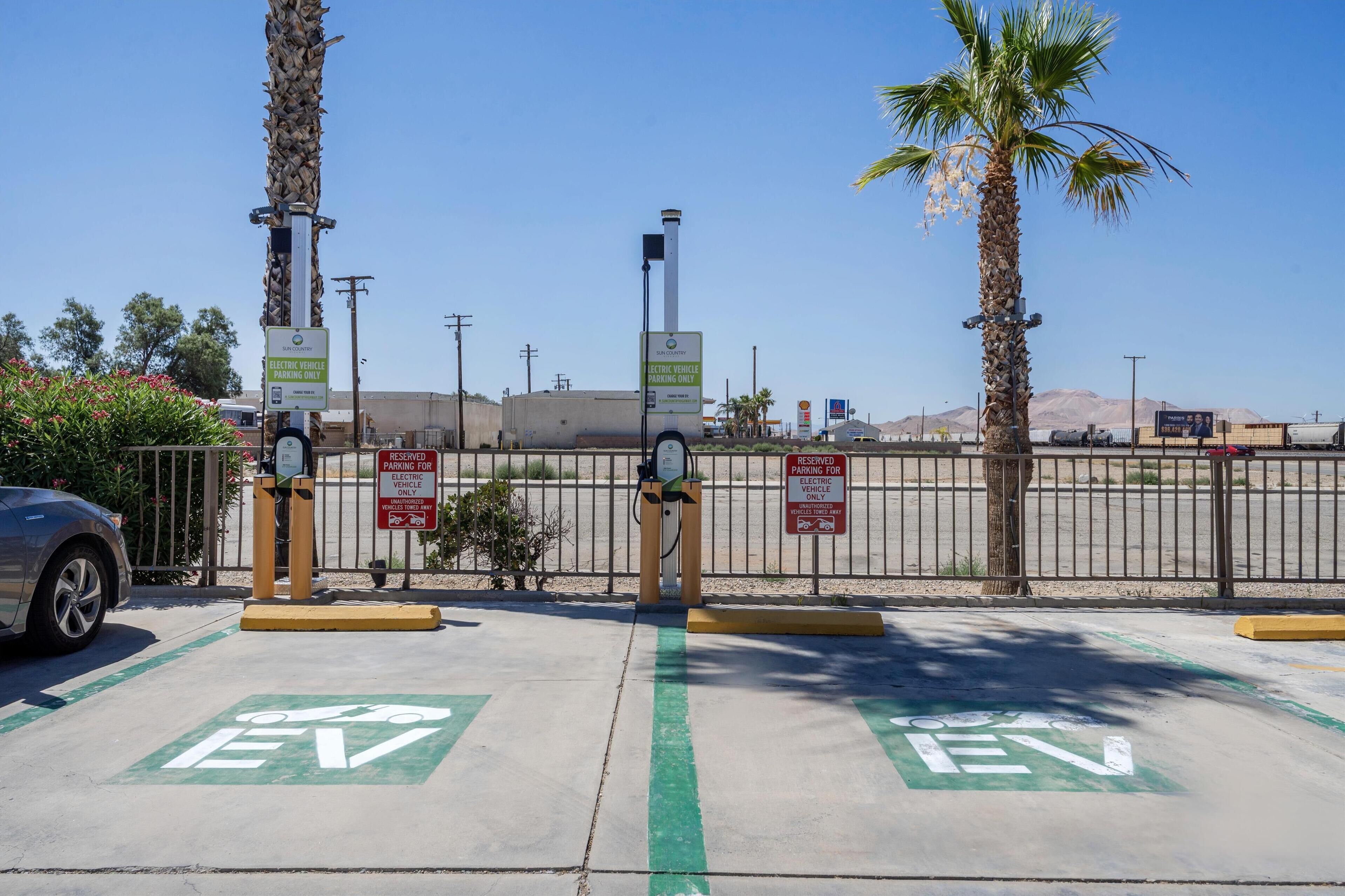 Un espace de stationnement équipé de bornes de recharge pour véhicules électriques, avec des emplacements de stationnement clairement indiqués pour les véhicules électriques et un panneau indiquant qu’il s’agit d’une zone de stationnement réservée.