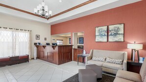 A hotel lobby with a reception desk, a sofa, a coffee table, and artwork on the walls. - Best Western Desert Winds (Mojave)