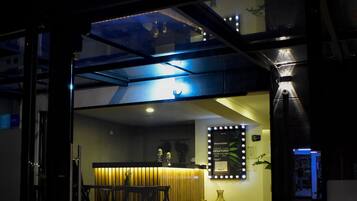 The exterior of DC Feria Hotel with a neon sign, a reception desk, and a staircase leading to the entrance.