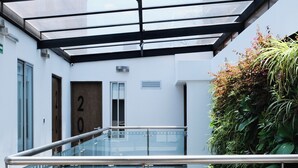 A modern building with a glass-enclosed atrium, a staircase, and a door labeled "20". - Hotel DC Feria (Bogotá)