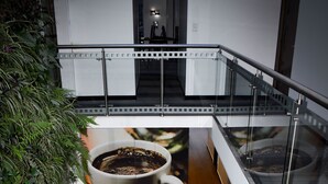 A modern interior with a staircase, a coffee-themed mural, and a seating area with a small table and chairs. - Hotel DC Feria (Bogotá)