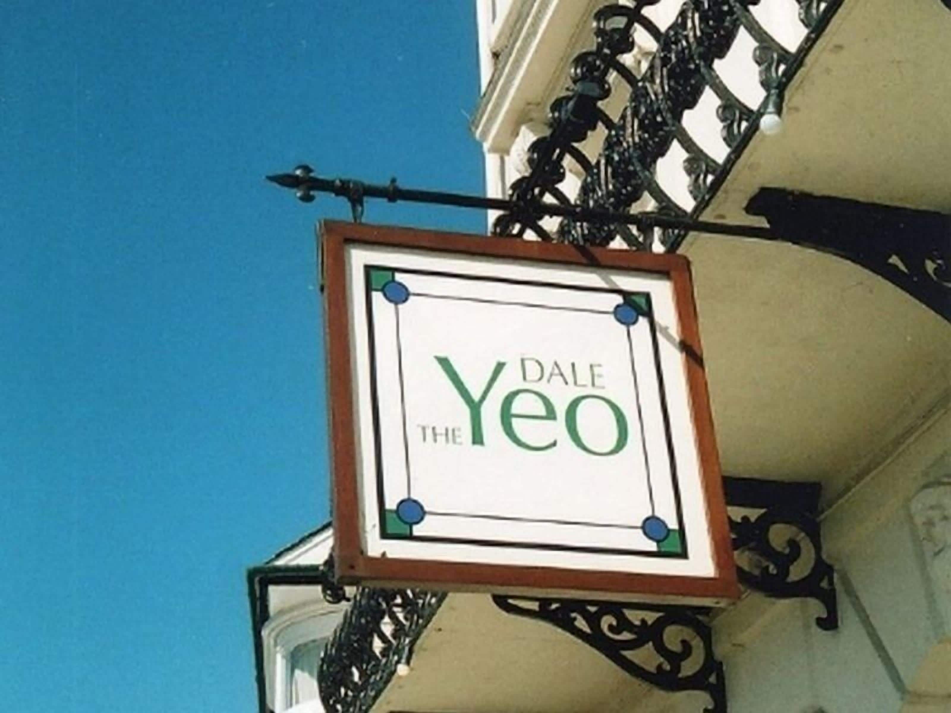 A sign for 'Dale The Yeo' hanging from a balcony with ornate metalwork.