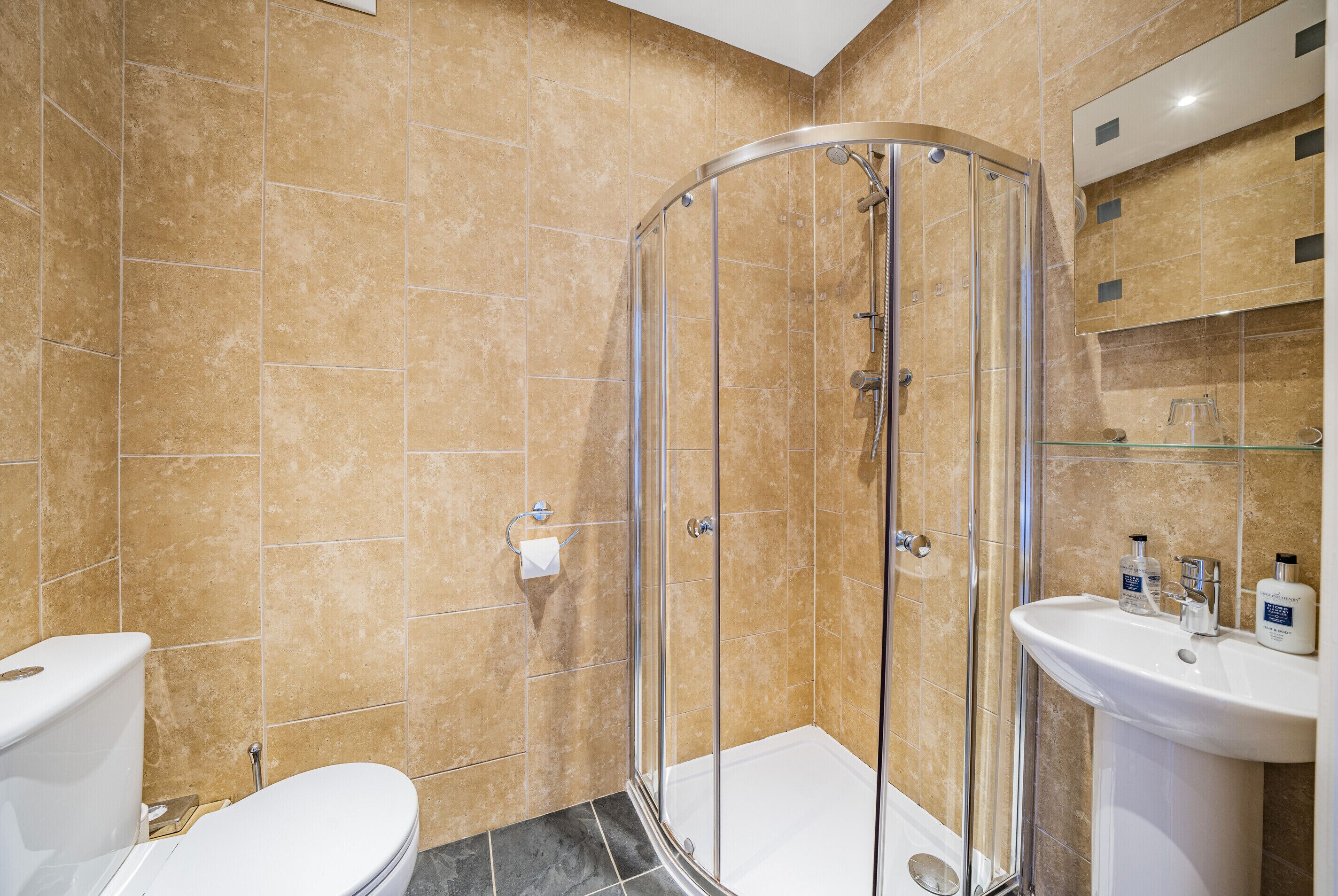 A bathroom with a glass-enclosed shower, a white sink, and a toilet.