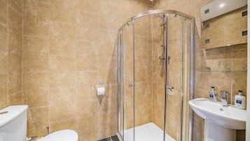 A bathroom with a glass-enclosed shower, a white sink, and a toilet.