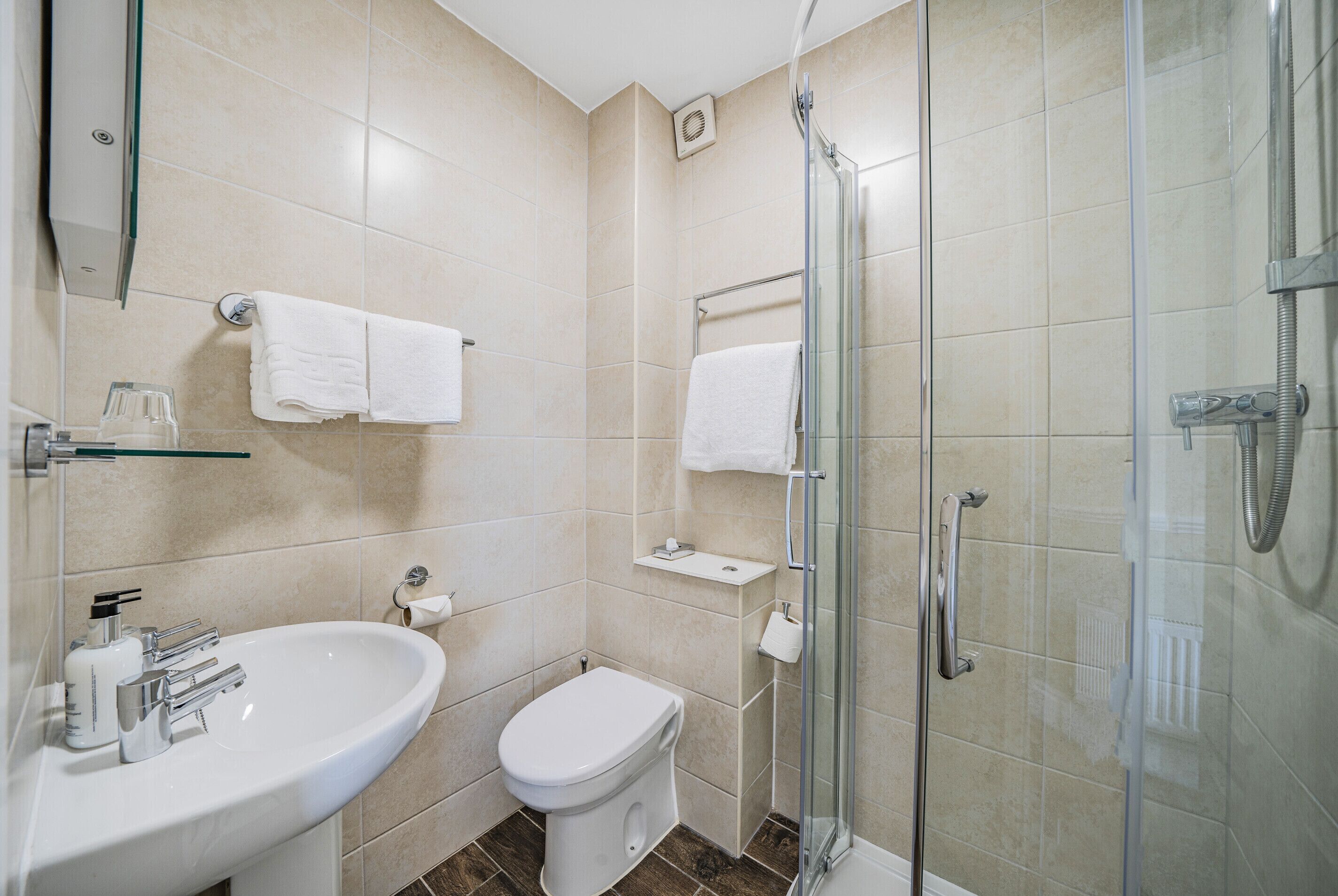 A modern bathroom with a sink, toilet, and glass shower enclosure.