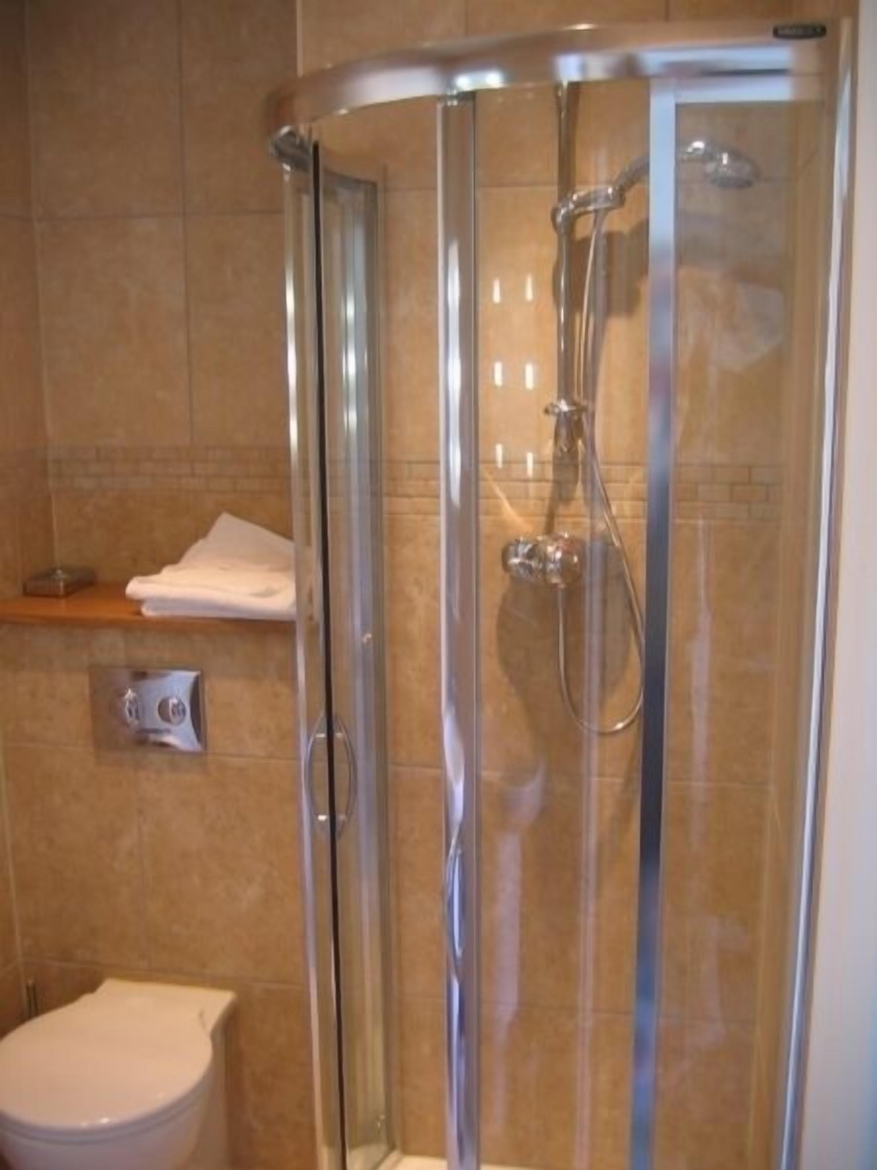 Un baño moderno con ducha de vidrio, inodoro y perchero para toallas.