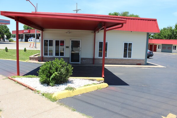 A small, single-story motel with a red roof and a covered front porch. - Guest House Motel (Carthage)