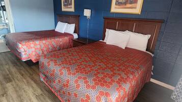Une chambre d’hôtel avec deux lits, un plancher en bois, des murs bleus et des tableaux encadrés accrochés au mur.