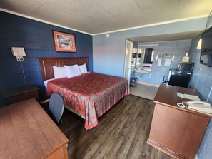 A hotel room with a bed, a desk, a chair, a bathroom visible through an open door, and a telephone on the desk. - Guest House Motel (Carthage)
