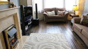 A living room with a fireplace, a sofa, a television, and a lamp. - Melrose Guest House (Douglas)