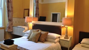 A hotel room with a large bed, two bedside tables, a mirror, and a window with curtains. - Melrose Guest House (Douglas)