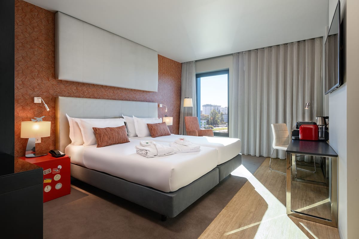 Ein modernes Hotelzimmer mit einem großen Bett, einem Schreibtisch und Blick auf die Stadt.