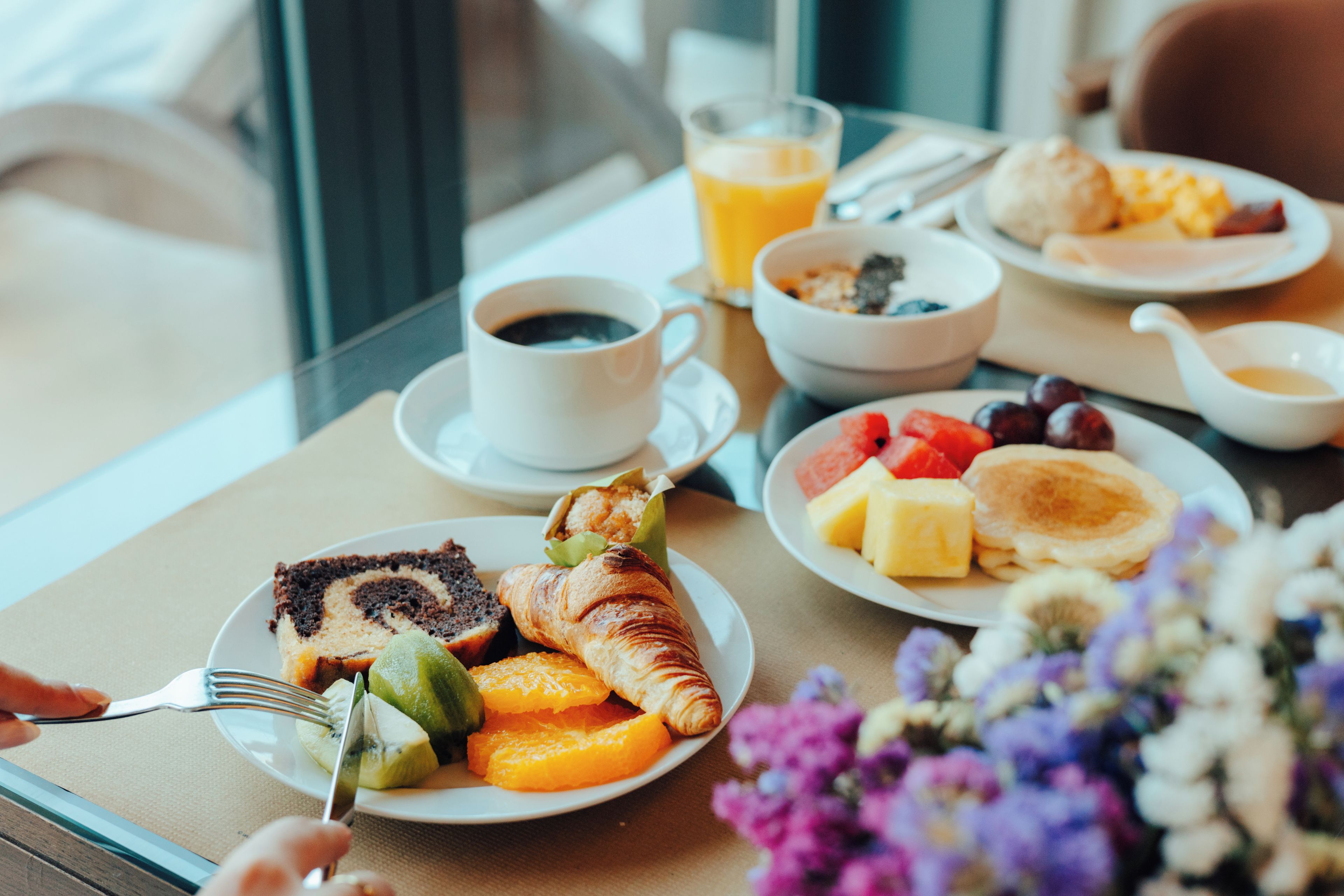 A breakfast setting with plates of food, a cup of coffee, and a glass of orange juice.