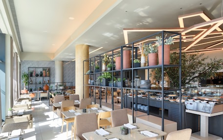 A modern restaurant with a variety of seating options, including tables and chairs, and a central display case with food items.