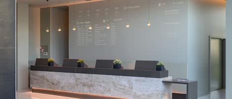 En modern receptionsdisk med en marmorskiva, flera lampor och en projektor som visar information.