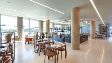 Un comedor amplio y moderno con techos altos, ventanas grandes y diversas opciones de asientos.