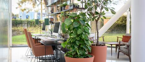 A modern dining area with a glass wall, a staircase, and potted plants.