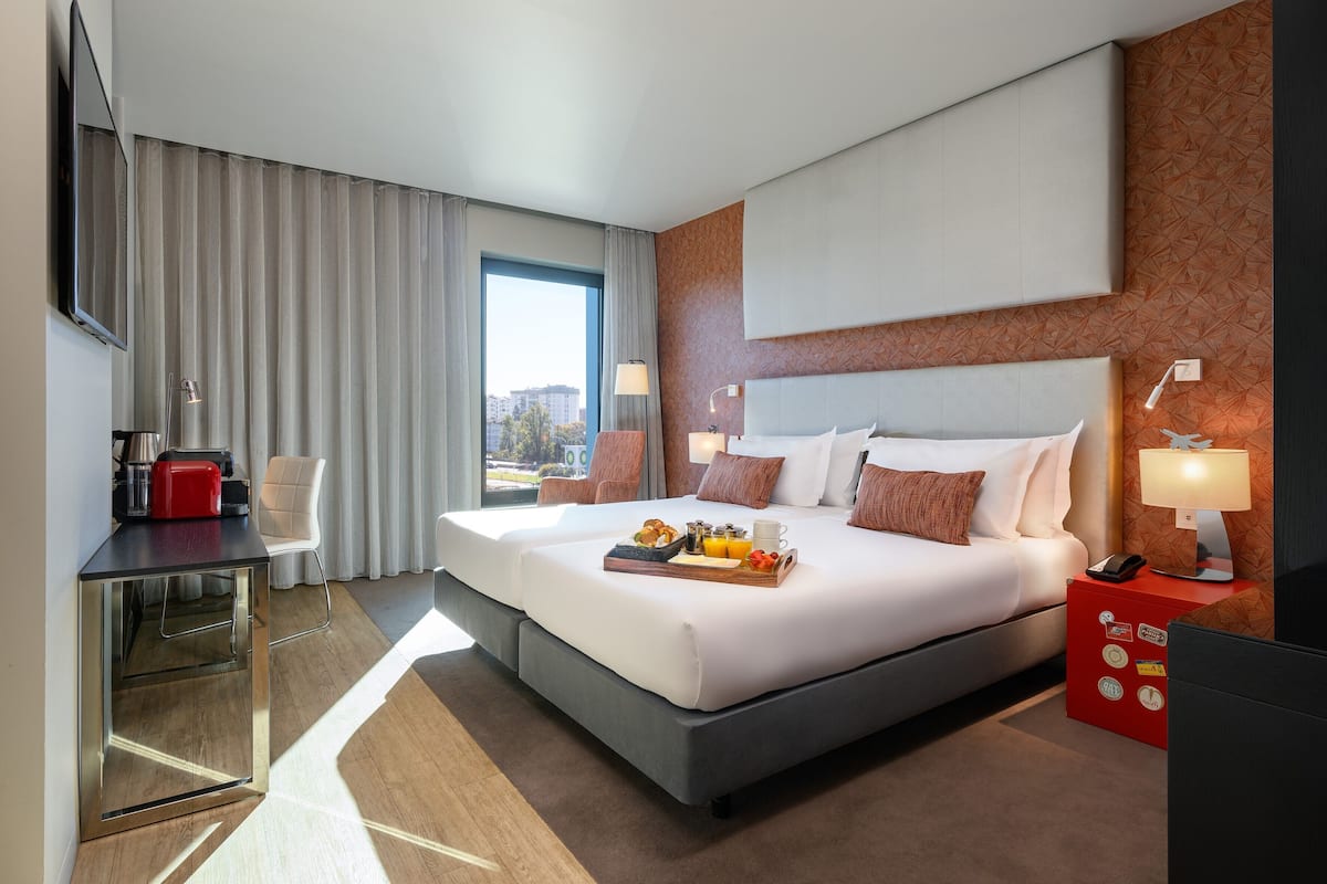 Ein modernes Hotelzimmer mit einem großen Bett, einem Schreibtisch und Blick auf die Stadt.