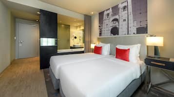 A hotel room with a large bed, a bedside table with a lamp, a mirror, and a painting on the wall.