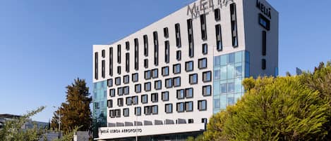 A modern building with the name "MELIA" on the facade, featuring a grid of windows and a sign for "MELIA LISBOA AEROPORTO".