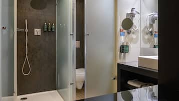 A modern bathroom with a glass-enclosed shower, a toilet, and a vanity with a mirror and sink.