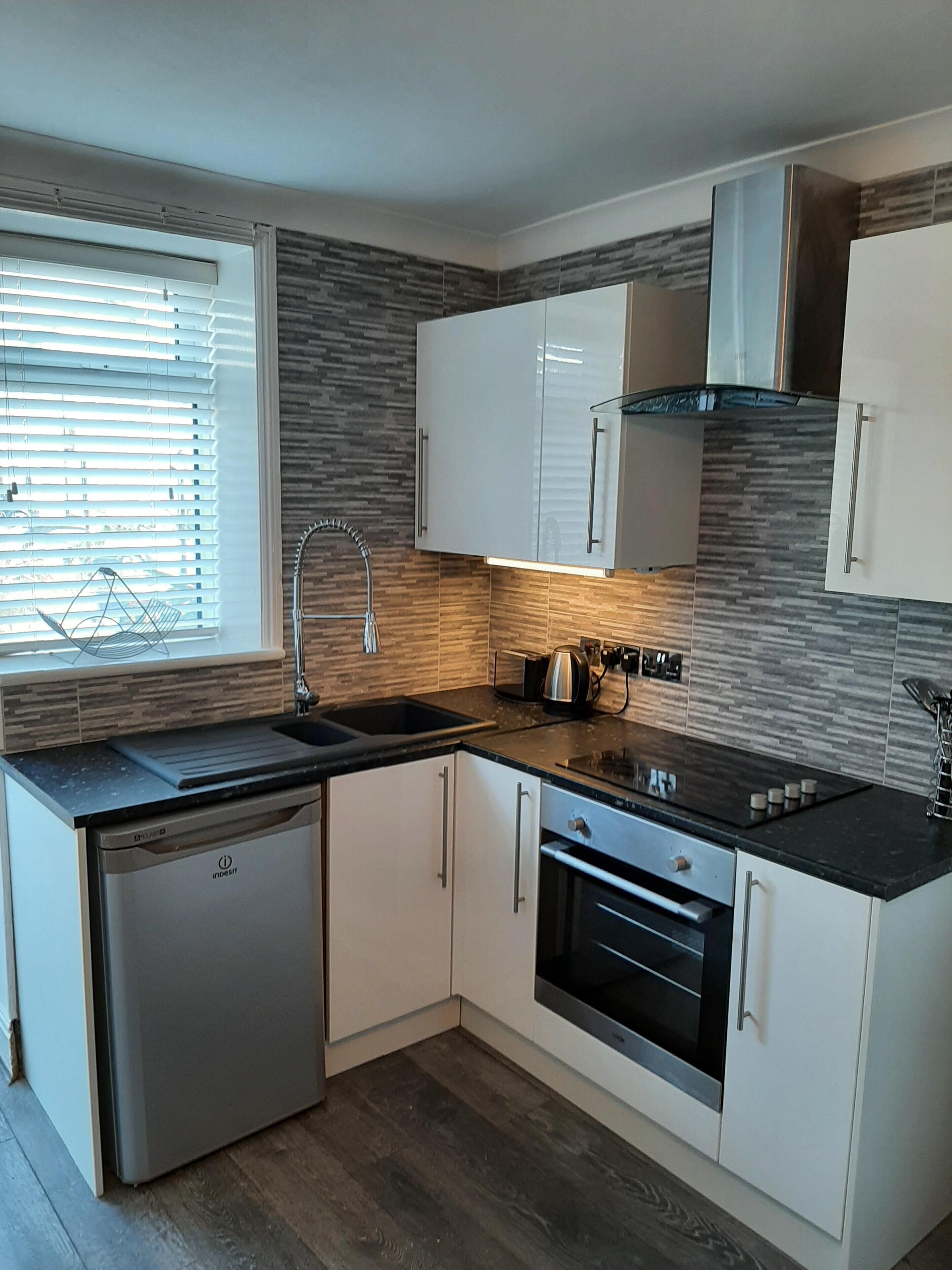 A modern kitchen with white cabinets, a built-in oven, and a dishwasher.