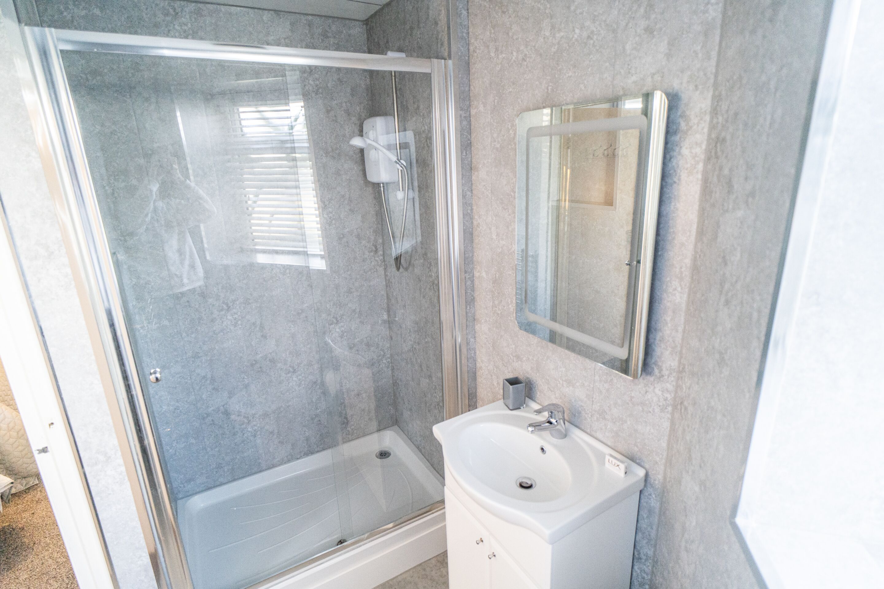A bathroom with a glass-enclosed shower, a sink, and a mirror.