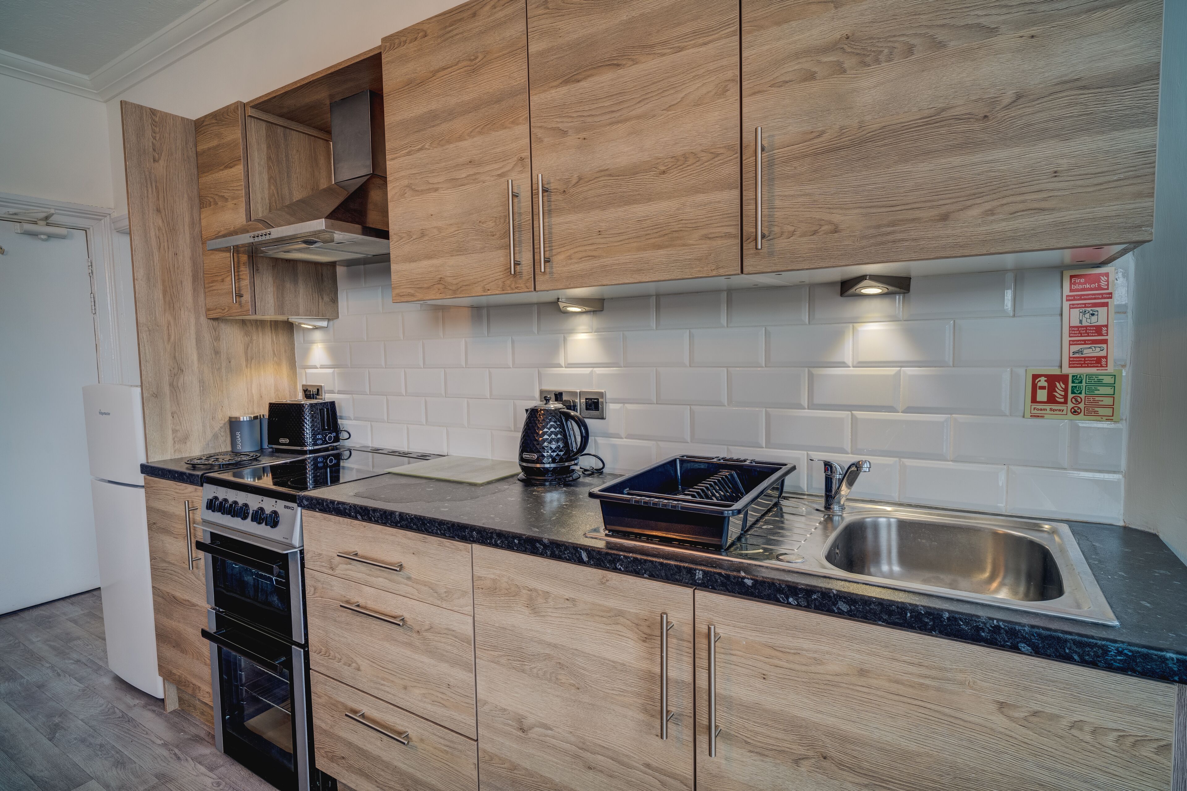 A modern kitchen with wooden cabinets, a stainless steel sink, and a built-in oven.