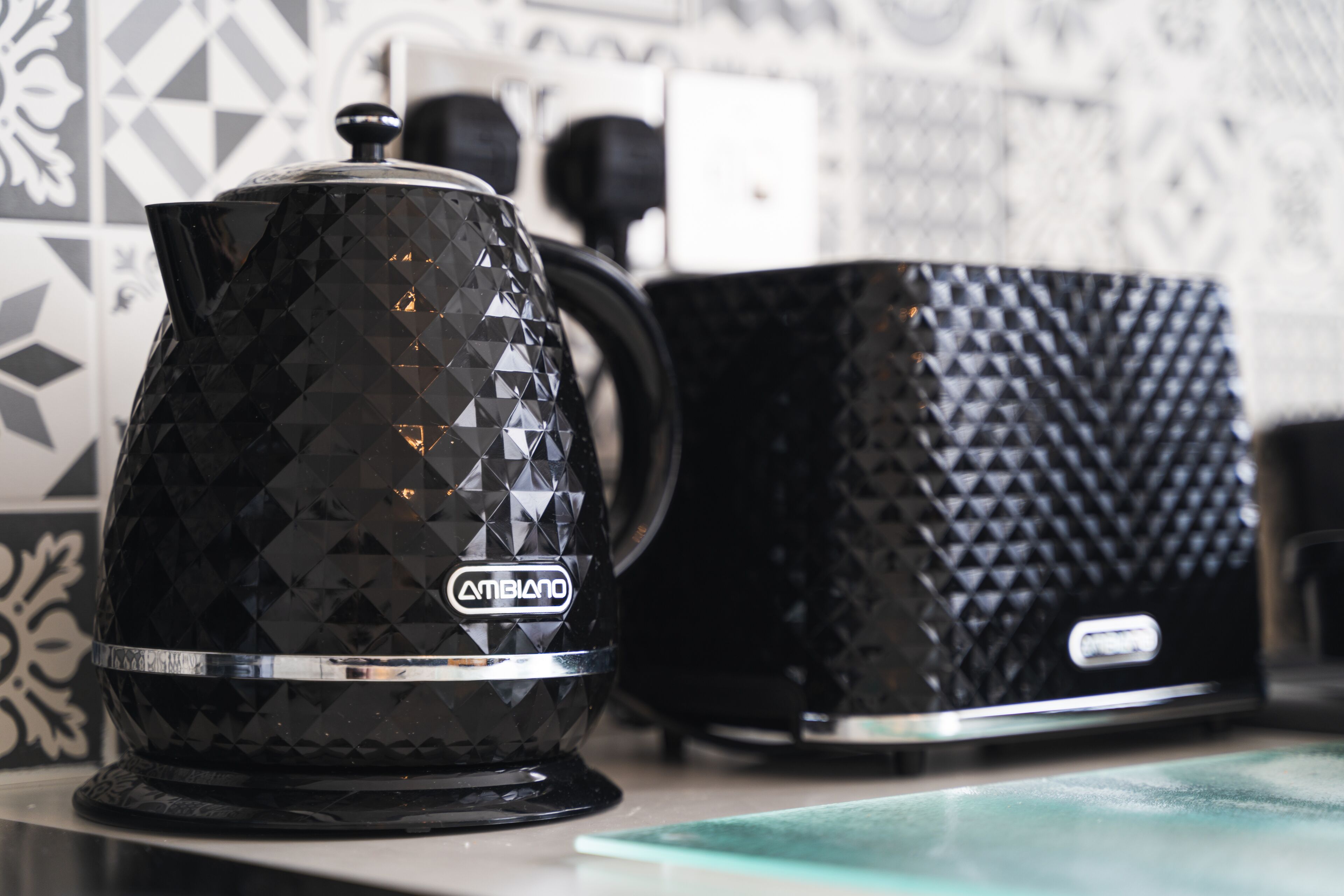 A black coffee maker with a diamond pattern and a brand name on a kitchen counter.