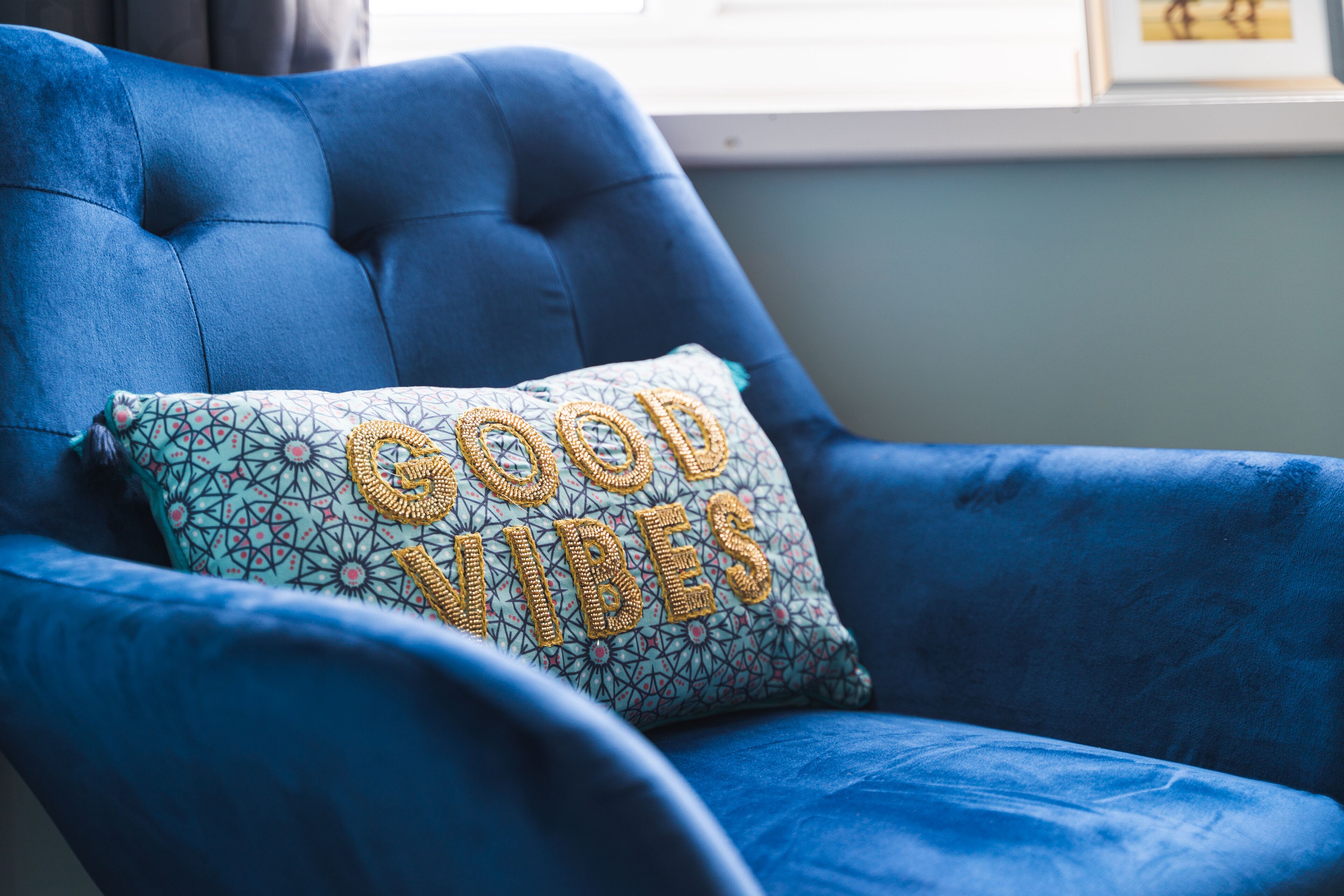 Un fauteuil bleu recouvert de tissu, agrémenté d’un coussin sur lequel est inscrit « BONNE AMBIANCE ».
