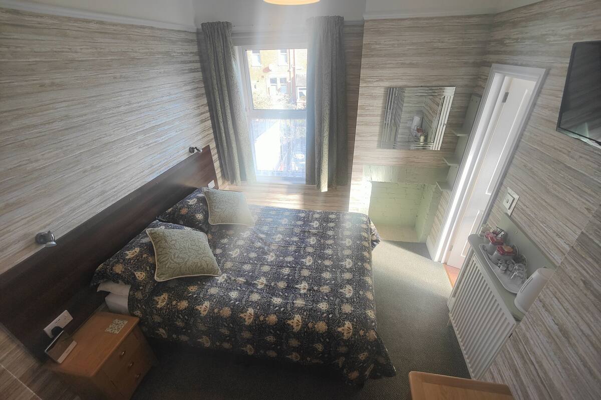 Une chambre d’hôtel comprenant un lit, une table de chevet et un petit bureau avec une chaise.