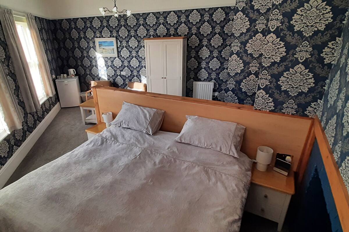 Une chambre à coucher comprenant un lit, des tables de chevet, une armoire et un petit coin cuisine.