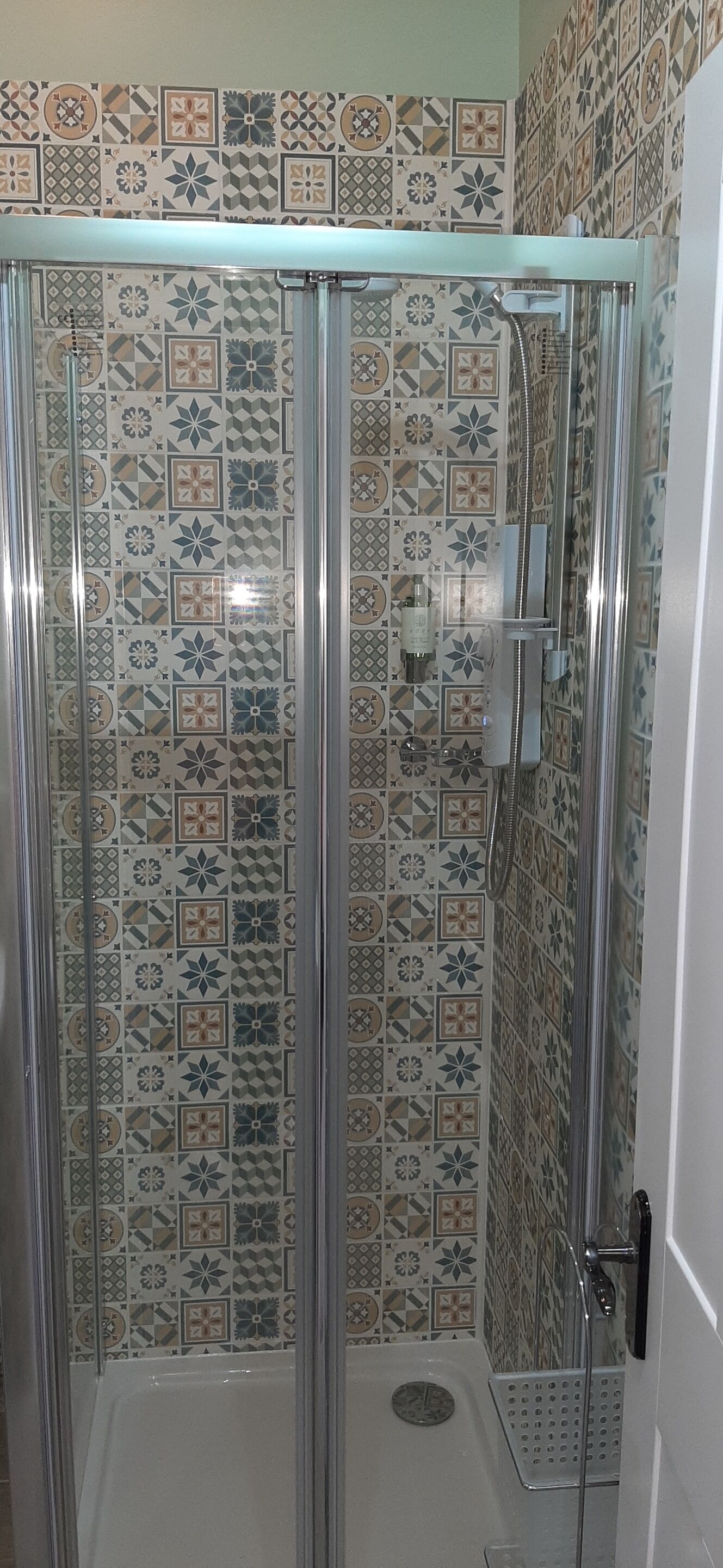 Eine Duschkabine mit Glastür und Duschkopf.