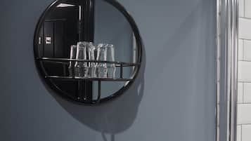 A bathroom with a round mirror, a white sink, and a glass shower enclosure.