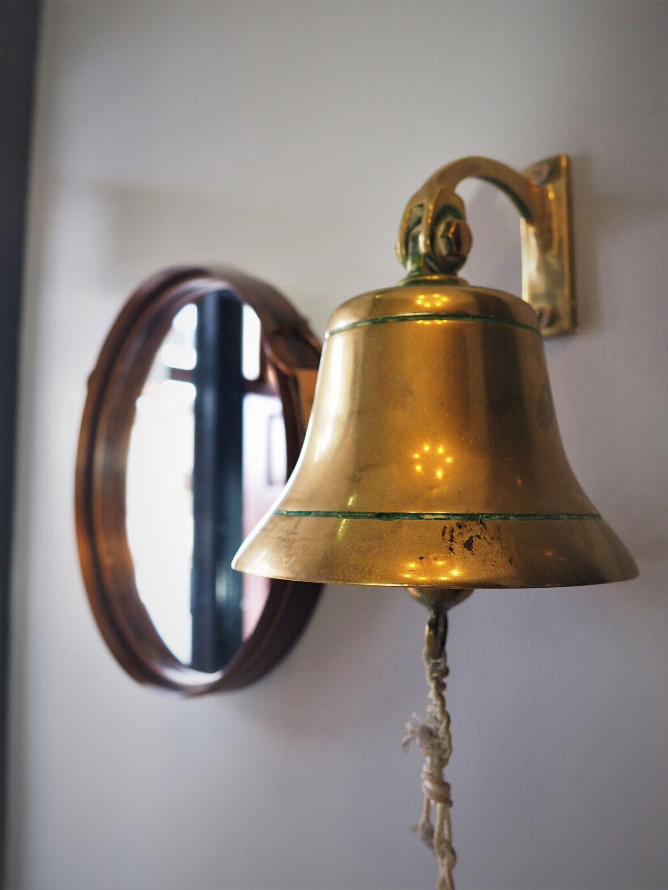 Una campana de bronce fijada a la pared con una cuerda colgando de su parte inferior.