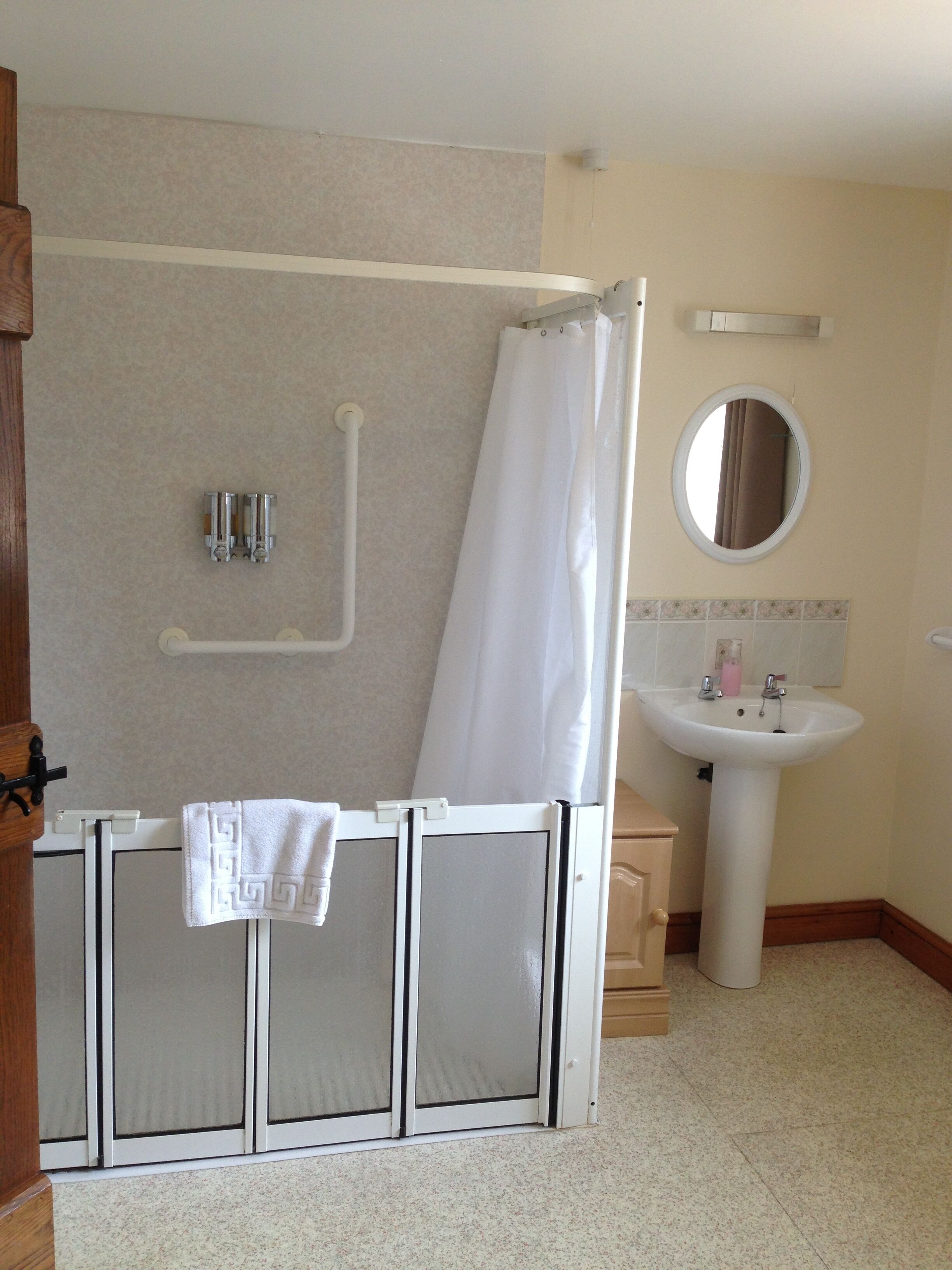 Un baño con ducha, lavamanos y espejo.