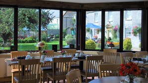 Comedor con ventanas amplias, sillas de madera y un ventilador de techo.
