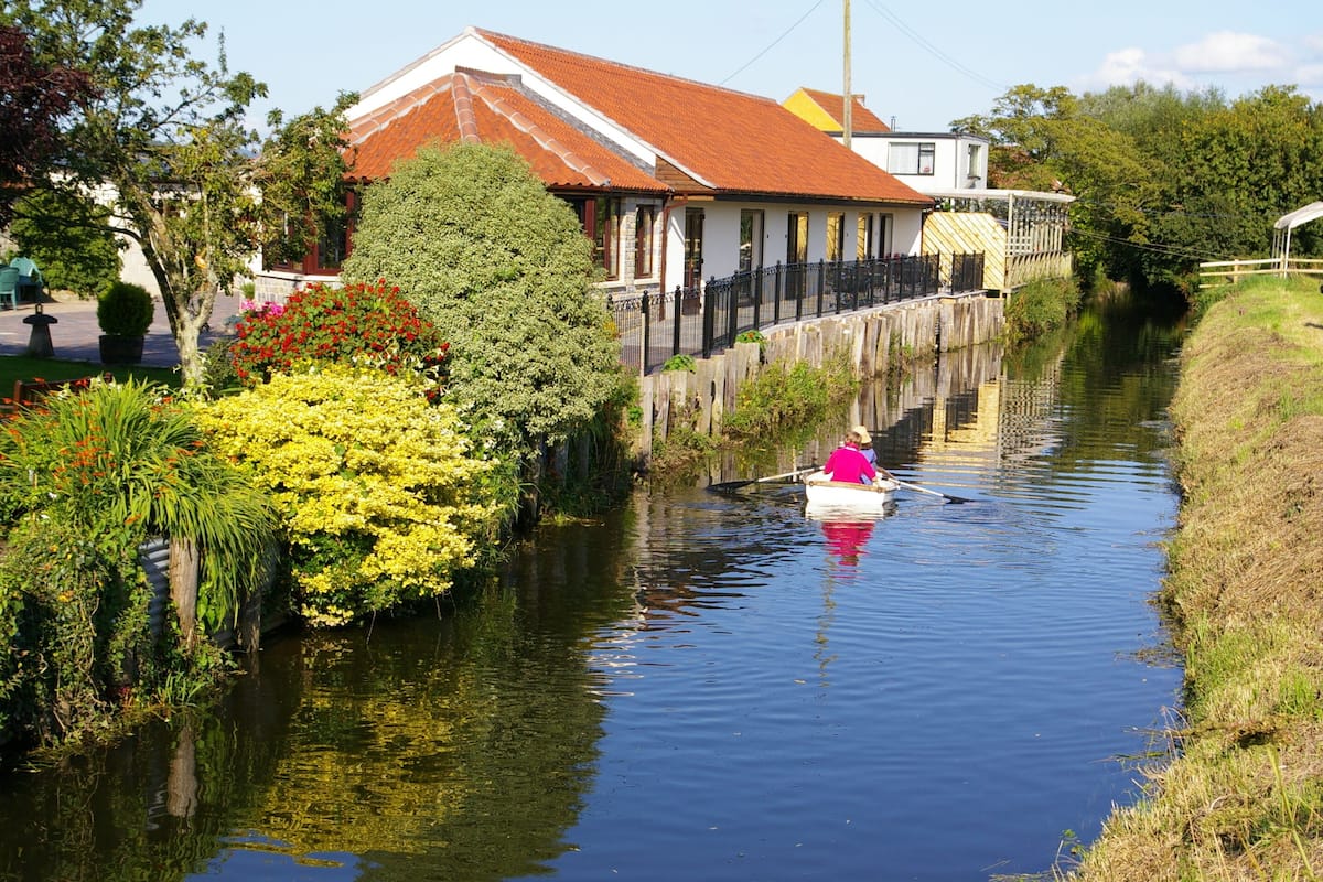 A narrow waterway with a house on one side and lush greenery on the other.