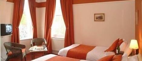 Een hotelkamer met twee bedden, een stoel, een tafel en een televisietoestel.