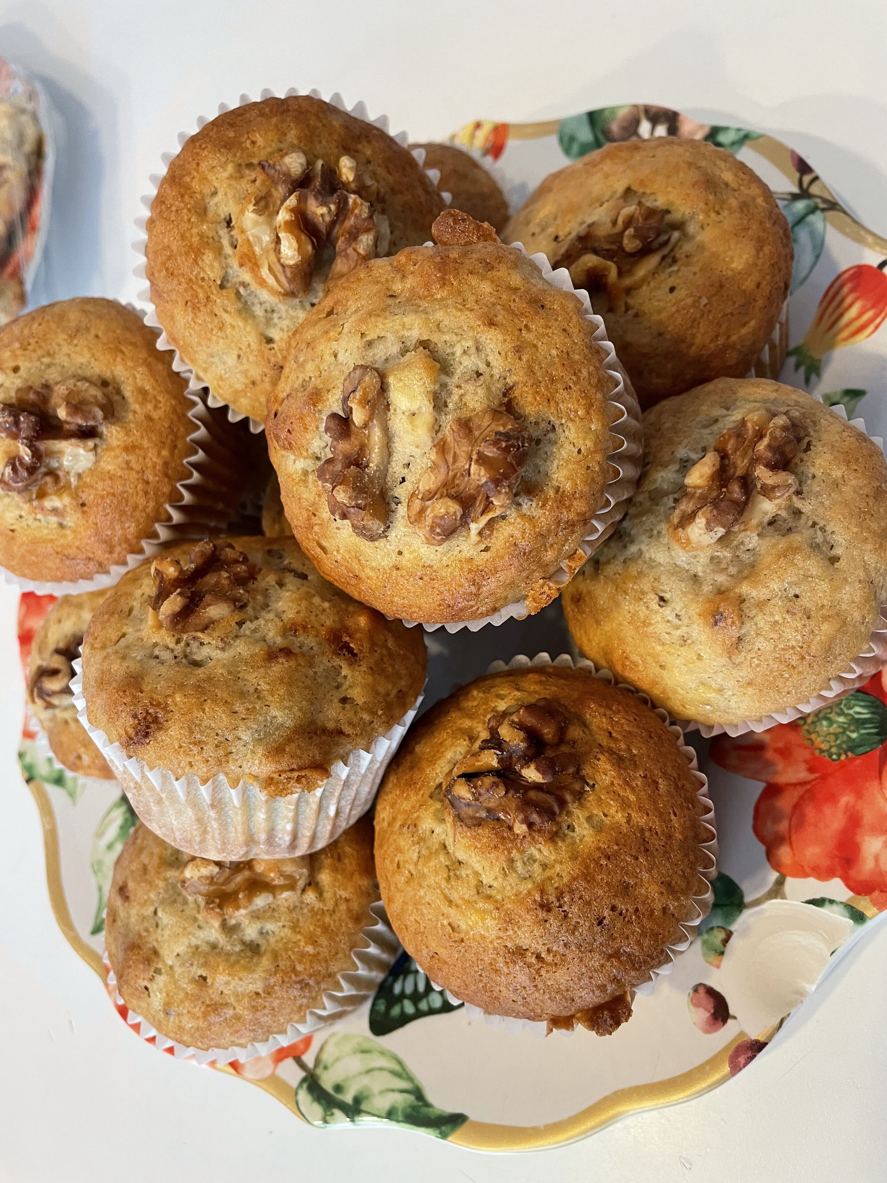 Ein Teller mit Muffins und Walnüssen auf einer blumigen Tischdecke.