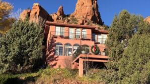 A two-story building with a balcony, surrounded by trees and red rock formations. - The Penrose Bed and Breakfast (Sedona)