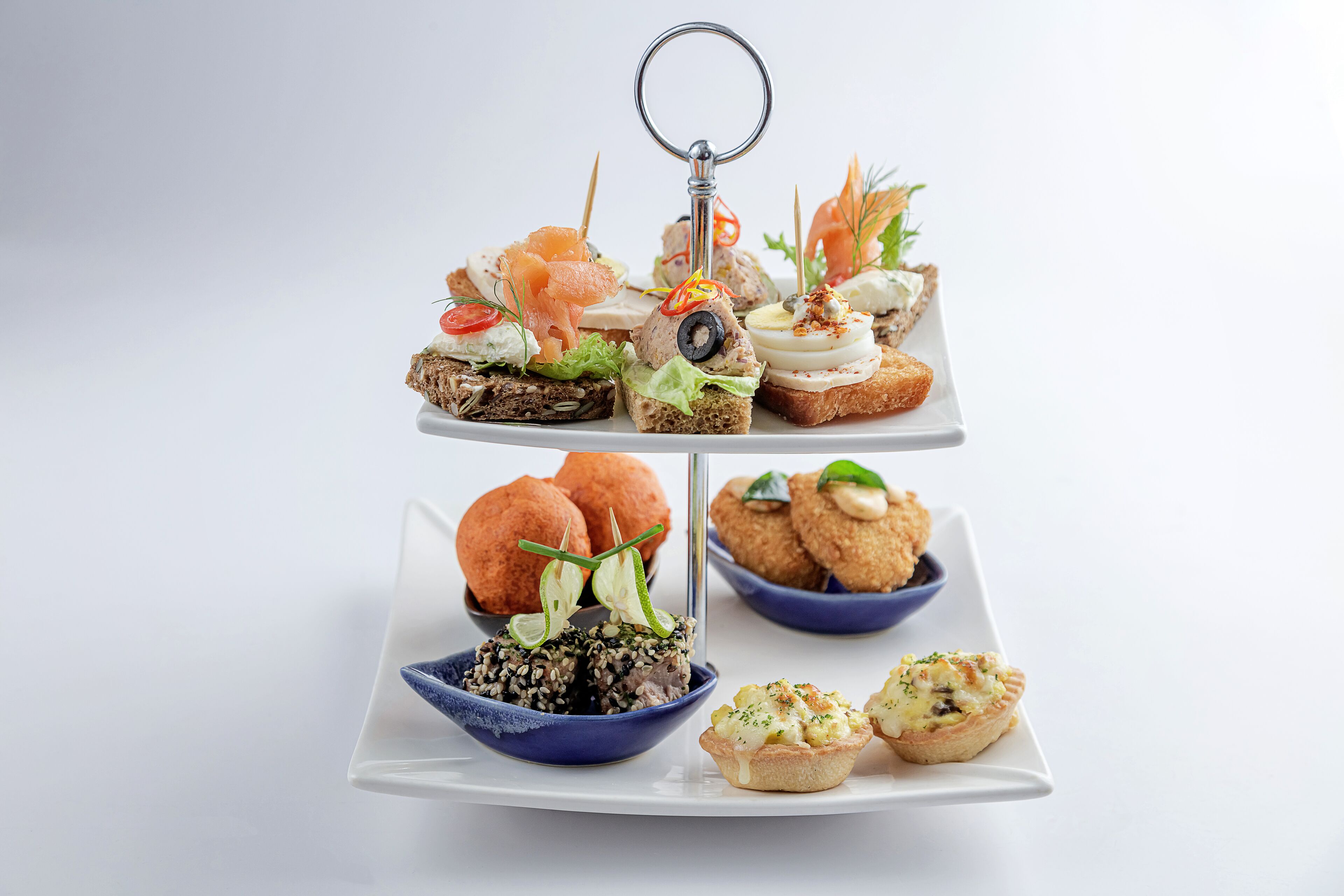 A three-tiered appetizer platter with various finger foods and a key ring.